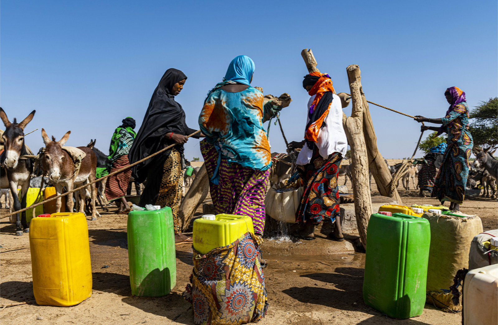 Eine Gruppe von Frauen füllt ihre Wasserkontainer an einer Wasserstelle auf