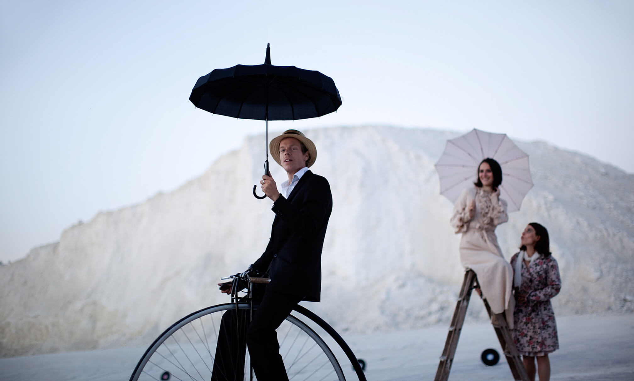 Künstler Dunkelbunt sitzt auf einem Einrad und hält einen Schirm