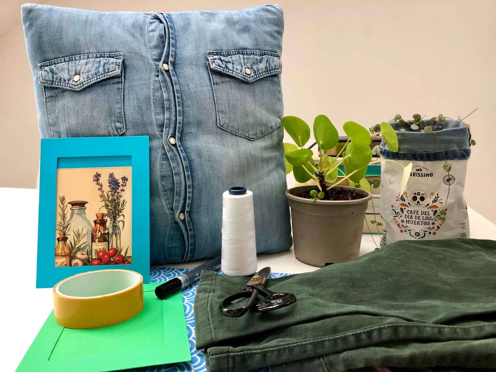 Ein selbstgenähter Posterbezug aus Jeans, eine Pflanze mit Ableger, ein Übertopf aus einem Kaffeesackerl und andere Gegenstände, die man tauschen oder mit denen man Basteln kann zur Illustration des Textes