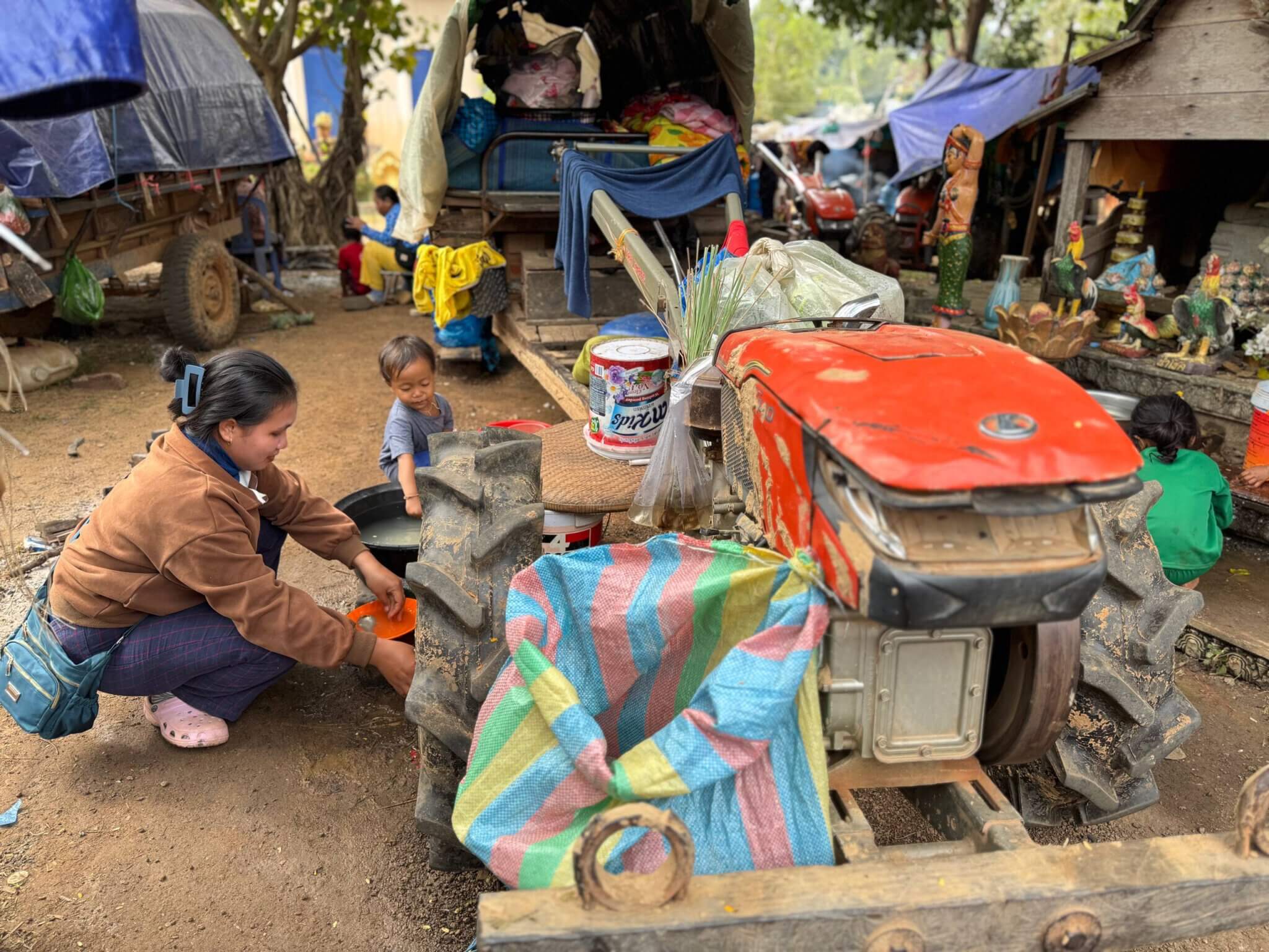 Eine Frau und ein kleines Kind bei einem umgebauten Traktor, der im Lager Wat Por Keo Meanchey den Geflüchteten als Küche dient